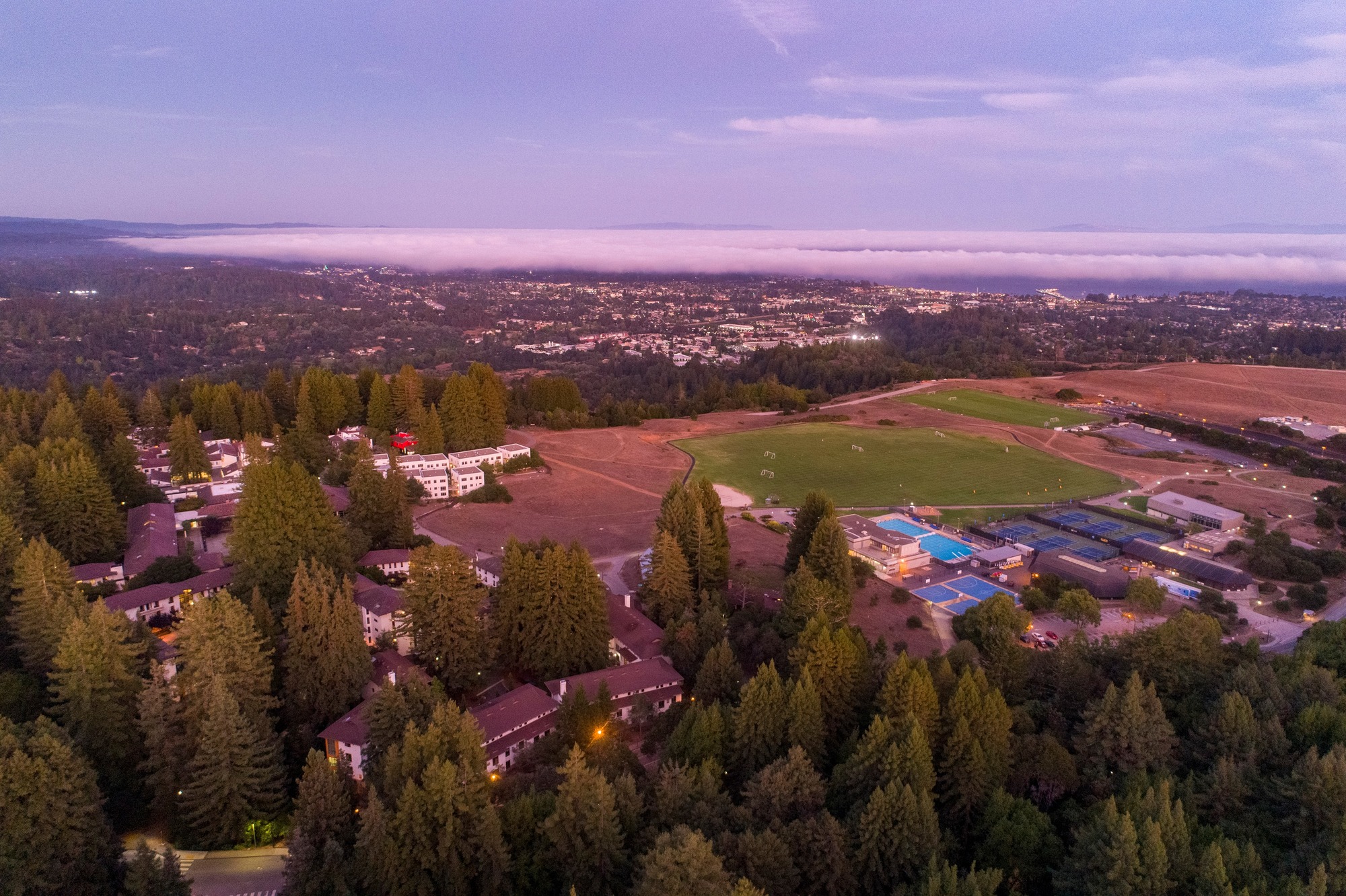 Aerial shot of campus at sunset with Santa Cruz city in the background.