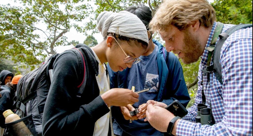 Student and teacher looking at specimen at outdoor class